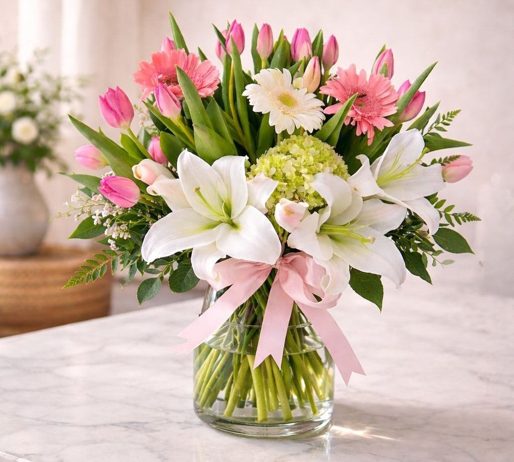 Arreglo floral elegante con lirios blancos, tulipanes rosados, gerberas y hortensia verde en diseño natural,