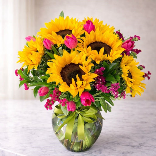 Arreglo de girasoles con tulipanes rosas y flores frescas en base de vidrio, disponible con flores a domicilio en Monterrey con entrega el mismo día.