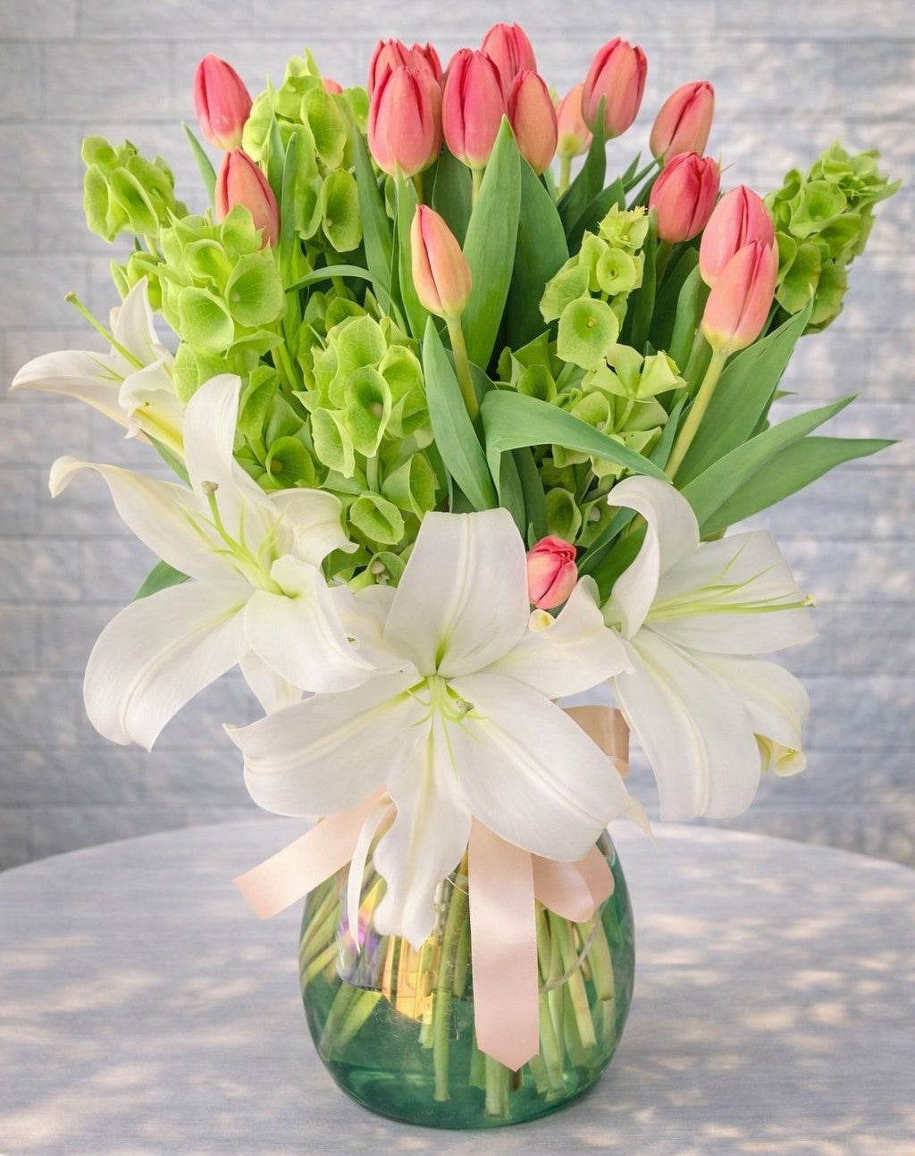 Arreglo premium con lilies blancos, tulipanes rosa y campana de Irlanda en florero Pink Rose Monterrey