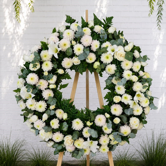 Corona de condolencias con flores blancas para funeral, disponible en Monterrey.