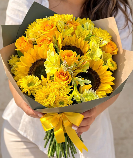 Mujer sosteniendo un ramo de girasoles y rosas amarillas ideal para regalar con entrega de flores a domicilio en Monterrey.