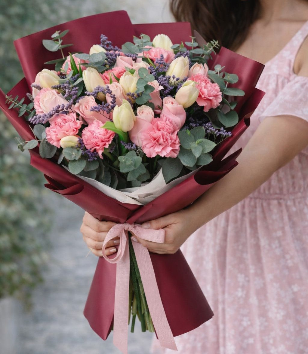 Ramo romántico de rosas rosadas, tulipanes y flores mixtas en envoltura elegante color vino con envío de flores a domicilio en Monterrey.