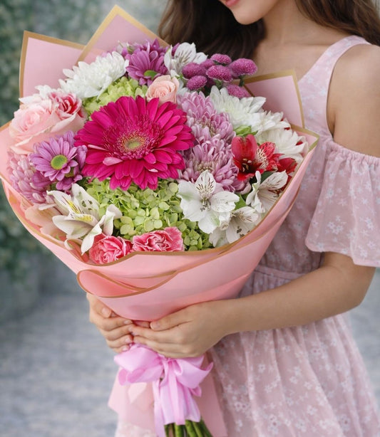 Ramo romántico de flores rosadas con gerberas, rosas y crisantemos en envoltura elegante rosa con envío de flores a domicilio en Monterrey.