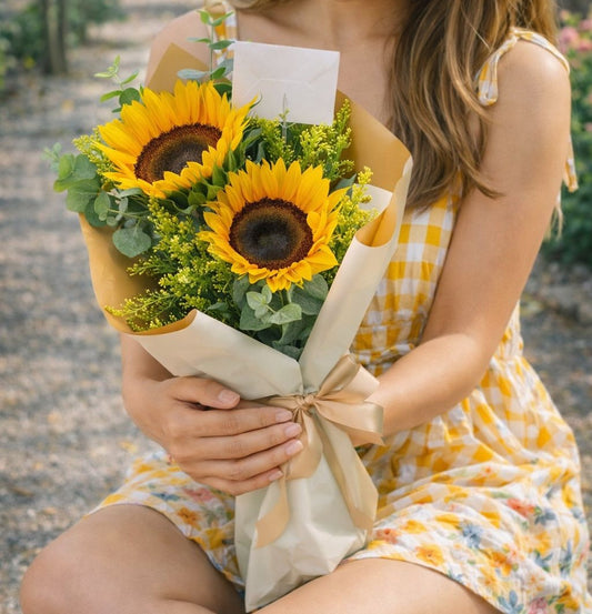 Mujer sosteniendo un hermoso ramo de girasoles frescos con follaje natural ideal para envío de flores a domicilio en Monterrey.