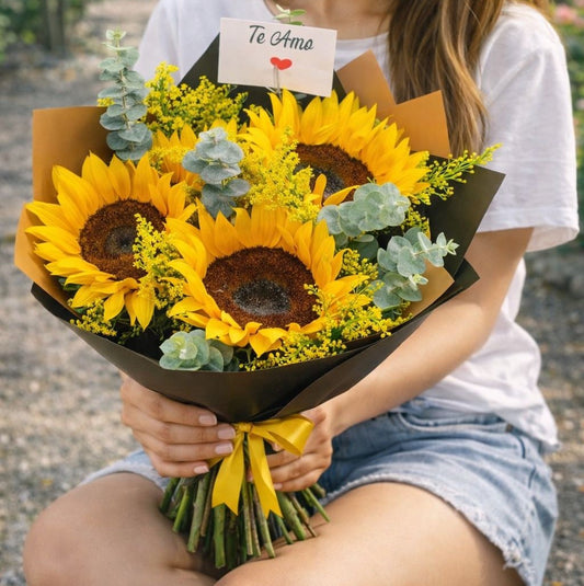Mujer sosteniendo un hermoso ramo de girasoles con tarjeta de amor ideal para envío de flores a domicilio en Monterrey.
