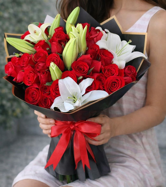Ramo premium de rosas rojas con lirios blancos y envoltura elegante negra, disponible con flores a domicilio en Monterrey con entrega el mismo día.