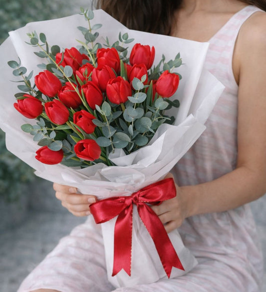 Ramo de tulipanes rojos con follaje verde y envoltura elegante blanca, disponible con flores a domicilio en Monterrey con entrega el mismo día.